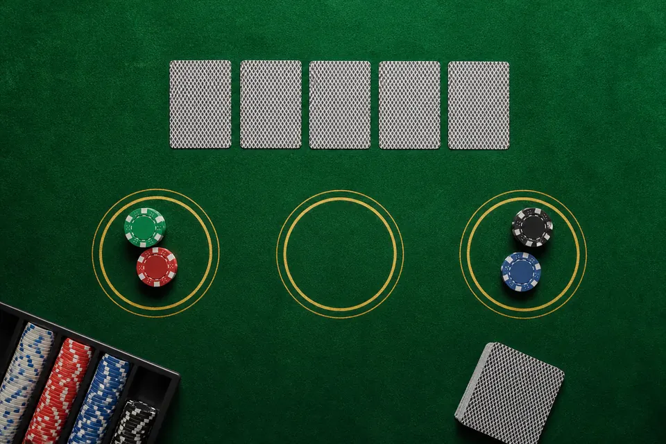 Pokerbord i casino sett ovanifrån med fem nedvända kort, tre insatsringar och marker