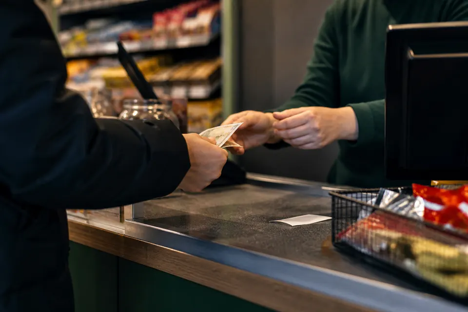 Kund som betalar med sedlar vid en kioskdisk